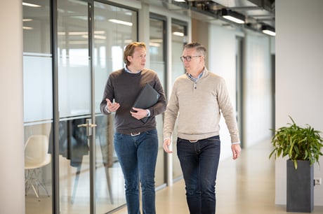 Two ISPnext colleagues walking through an office hallway discussing e-invoicing software